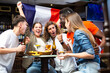© JackF - Group of cheerful young adult women and men having fun in sports bar, watching game on TV and rooting for favorite French team