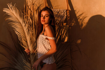 Canvas Print - Portrait of an attractive young woman posing and enjoying a covered palm leaf outside a tropical house.