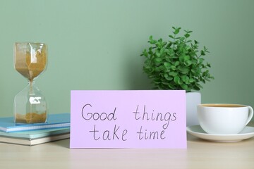 Wall Mural - Phrase Good Things Take Time, coffee, houseplant and hourglass on table against light green background. Motivational quote