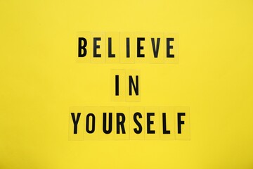Phrase Believe In Yourself and hearts on yellow background, top view. Motivational quote
