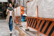 © PR Image Factory - full length of Asian Japanese girl pedestrian passing by a construction site with orange safety barrier fence while walking on street in osaka city japan
