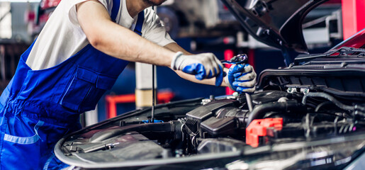 Professional car technician mechanic team in uniform work fixing vehicle car engine and maintenance repairing checking under the car hood in auto service. Automobile service garage