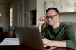 © gpointstudio - Cheerful adult man with down syndrome using laptop at home