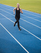 © Westend61 - Smiling young sportswoman running on track