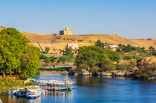Egypt, Aswan Governorate, Aswan, Tourboats Moored On Bank Of Nile River With Mausoleum Of Aga Khan In Background
