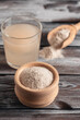 Psyllium husk powder in bowl and glass with of water soluble fiber for intestinal, old wooden table. Gluten free diet concept. Side view, selective focus, vertical