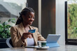 © Westend61 - Happy businesswoman holding credit card and using tablet PC at cafe