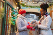 © Westend61 - Woman in warm clothing giving gift to friend on Christmas festival