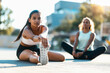 © Westend61 - Teenage girl practicing stretching exercise with friend sitting in background on sunny day