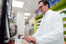 Pharmacist Using Desktop PC In Store