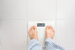 © Westend61 - Man standing on weight scale at home