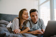 © Drobot Dean - White young couple using laptop while resting on bed together