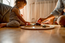 Father And Son Playing With Toy Train On Floor At Home