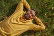 © Westend61 - Cheerful man in yellow hooded jacket lying on grass at park