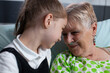 © DC Studio - Family members smiling happily at sanatorium nursing home. Girl showing affection to elderly patient with breathing aids in hospital room. Grandmother grateful for granddaughter visit at medical