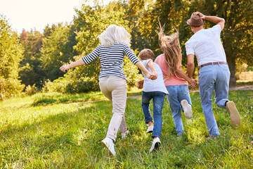 Wall Mural - Family and children running across a meadow