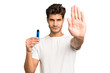 © Asier - Young caucasian man holding an electronic cigarette isolated standing with outstretched hand showing stop sign, preventing you.