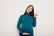 © Asier - Pregnant caucasian woman isolated on white background joyful and carefree showing a peace symbol with fingers.
