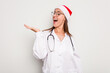 © Asier - Young caucasian doctor woman wearing a santa hat isolated on white background