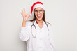 © Asier - Young caucasian doctor woman wearing a santa hat isolated on white background