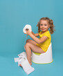 A child on the potty plays with toilet paper. Toilet training.