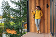 © Oleksandr Kozak - Young female in yellow down jacket with leather retro tourism backpack have a rest in nature background with cabin house behind