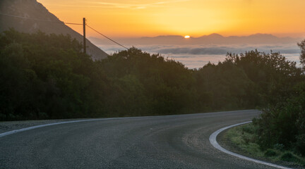 Wall Mural - a paved, empty road in corfu, greece at sunset