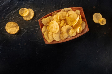 Wall Mural - Potato chips or crisps, shot from above on a black slate table with copy space