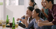 © ChayTee - Group of young adult friend man and woman asia people sit at sofa couch joy chanting party fun game FIFA world cup live TV at home eat snack bowl drink beer bottle glass jump mad happy win exult face.