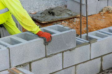 Canvas Print - Bricklayer is putting down another row of cement blocks as part of construction process