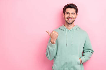 Sticker - Portrait photo of positive cheerful guy wear khaki trendy sweater put hand pocket directing finger empty space tips isolated on pink color background