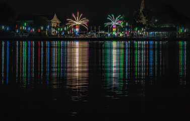 Riverside thai local temple fair work decorated with different colored lights and sky in night time. View from the opposite bank of the river, Celebration, Space for text, No focus, specifically.