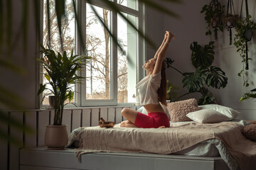 Young sporty woman practicing breathing yoga pranayama at home,sitting in Lotus position,holding breath while inhaling.Relaxation and meditation.Wellness,wellbeing,mental health concept.