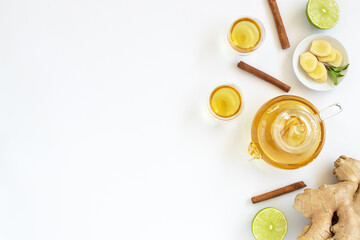 Wall Mural - Top view of a cup of tea with ginger root, lime, cinnamon and teapot on white background. Health drink concept.