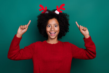 Wall Mural - Photo portrait of charming little girl excited point new year deer horns wear trendy red knitted clothes isolated on green color background