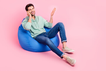 Wall Mural - Full length photo of positive man sit chair use modern telephone chatting communicating empty space isolated on pink color background