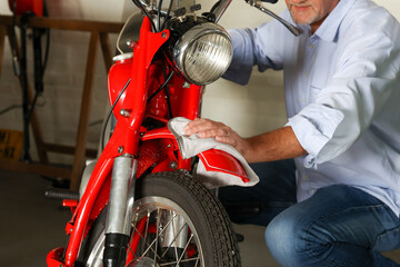 The man washing and cleaning motorbike. Detailing color polishing holds the soft microfiber cloth applying nano coating on a red metal steal polishing his classic motorcycle to get more shiny color. 
