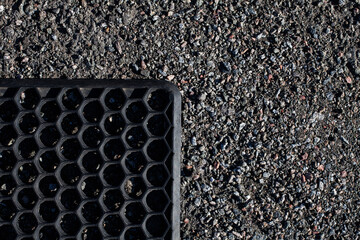 Rubber mat for feet, for wiping dirt lies on gravel, Surface grunge rough of asphalt, texture background, tarmac grey grainy road, top view.