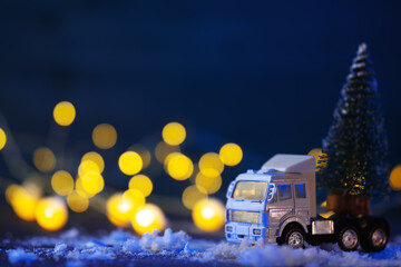 Wall Mural - Toy truck transports Christmas tree, festive background, bokeh garlands