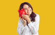 © Studio Romantic - Happy woman who is satisfied with her financial achievements holds piggy bank near her cheek. Smiling woman with closed eyes gently leans against piggy bank in form of red pig on orange background.