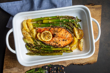 Grilled, baked salmon served on a plate with asparagus and potatoes