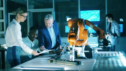 Wall Mural - functioning robotic arm with engineering team observing it