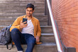 © ADDICTIVE STOCK - Concentrated man in casual outfit using smartphone on stairs