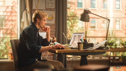 Leinwandbilder - Caucasian Man Designs Video Game on His Laptop Computer in a Stylish Office Space. Creative Male Makes Clothing For Character. Cool Game with Graphics and Fun Social Media Metaverse Gameplay.