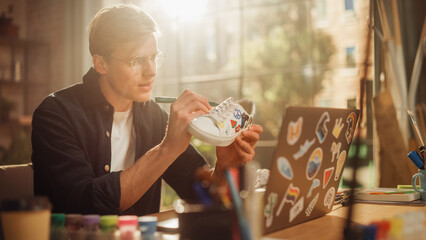 Poster - Talented Male Artist Working on Colourful Design for Sneakers, Uses Laptop Computer in Loft Office Studio. Fashion Designer Customising Pair of Shoes. Post Production Concept.