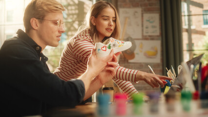 Leinwandbilder - Team of Teenage Fashion Designers Analysing and Discussing Concept of Custom Made Shoes. Smiling Woman Shares Her Ideas With Man. Young Promising Sneaker Artists Collaboration.