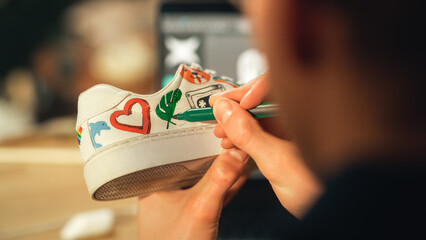 Poster - Male Artist Working on Colourful Design for Footwear in Loft Showroom. Fashion Designer Customising Pair of Shoes. Post Production Concept. Over the Shoulder View, Close-up.