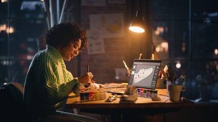Poster - Creating Trendy Design. Black Woman Feels Inspired While Drawing in the Evening. Female Designer Puts Patterns on Shoe Comparing with 3D Model on the Laptop Computer Screen.