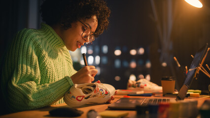 Leinwandbilder - Creative Black Female Designer Applying Her Own Patterns on Shoe, Using Prototype 3D Model on Laptop Screen. Stylish Studio in the Evening. New Generation Fashion Concept.