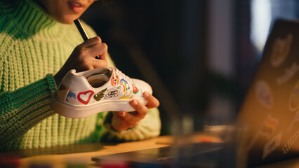 Leinwandbilder - Close Up of Black Female Designer Putting Her Unique Drawing on Shoes, Working Late in the Evening in Loft Living Room. Millennial People and Fashion Trends in Clothing Design Concept.